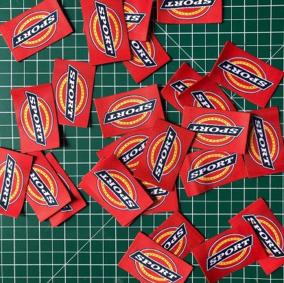 a pile of custom sport tags on green cutting mat